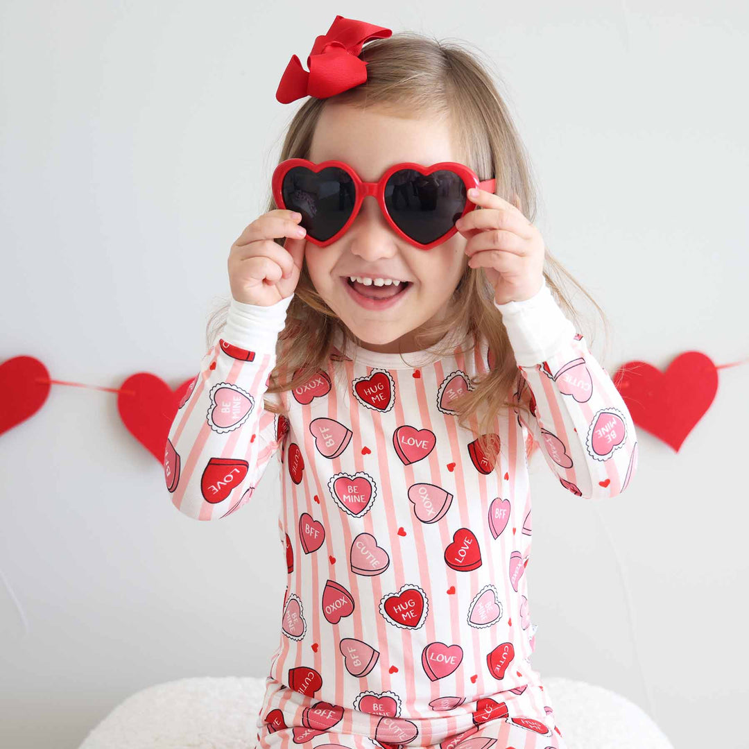 girl wearing the pink sweet like candy two piece pajama set with red heart sunglasses 