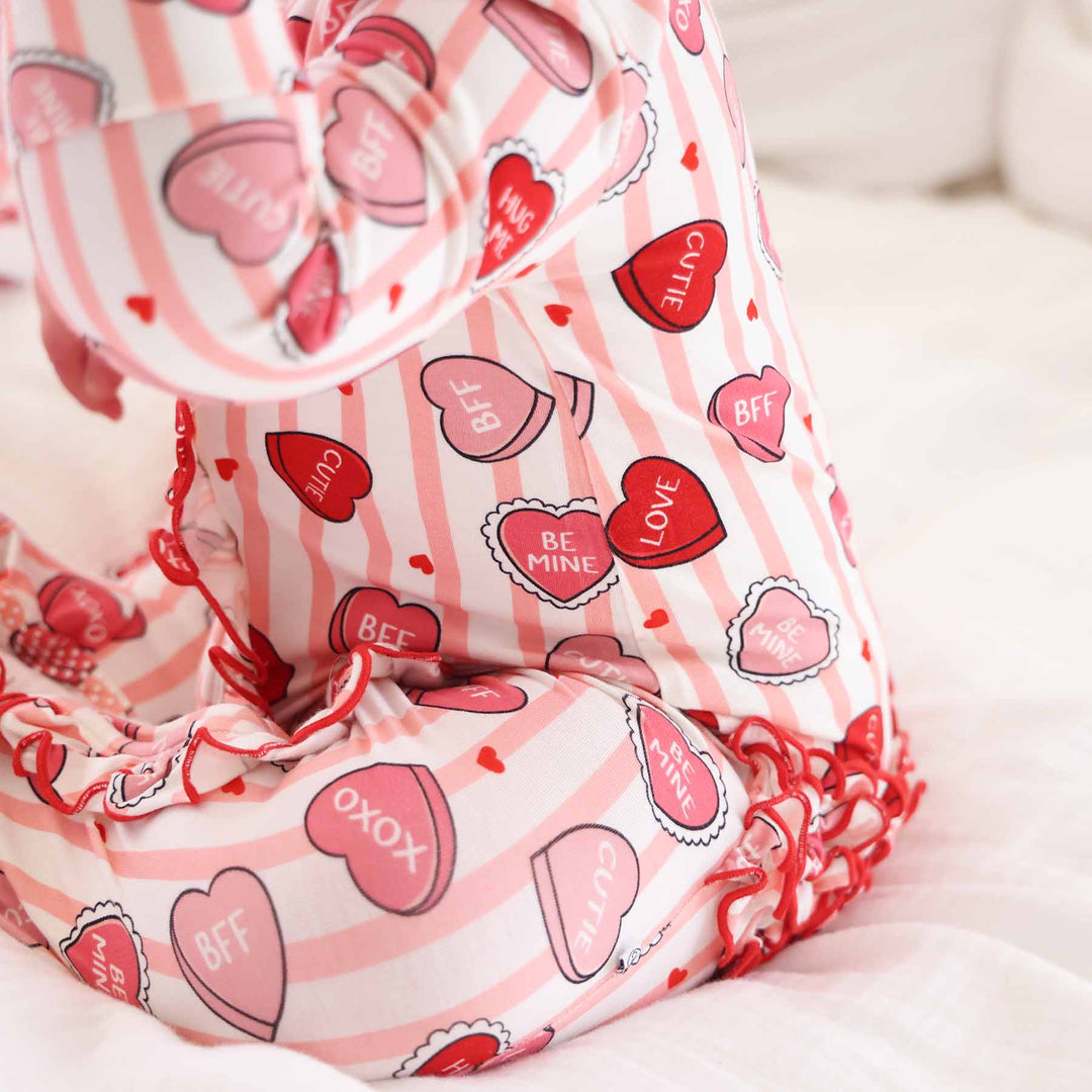 pink valentine's day baby girl footie with pink stripes, candy hearts and ruffles on the bottom 