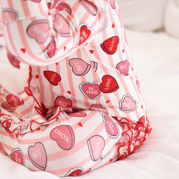 pink valentine's day baby girl footie with pink stripes, candy hearts and ruffles on the bottom 