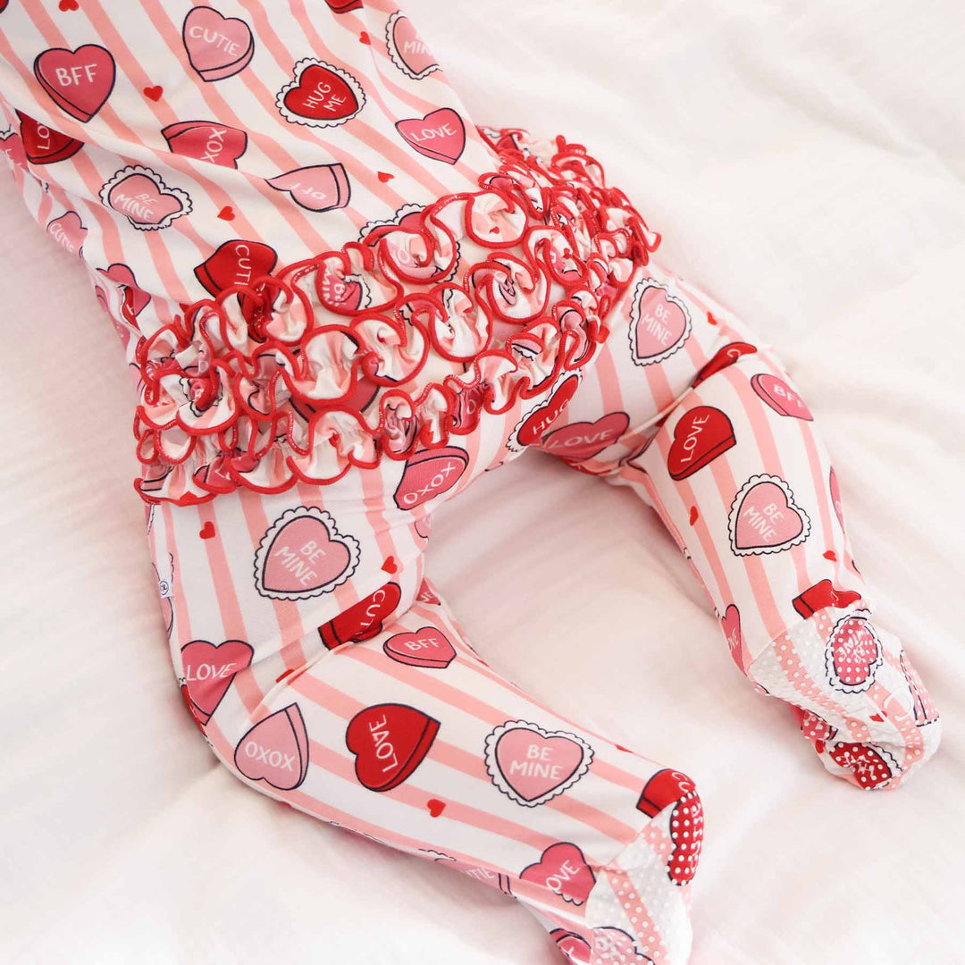 ruffle bottom valentine's day footie for babies with pink stripes and pink and red conversation heart candy