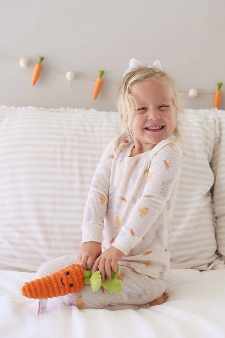 kneeling girl wearing sweet peep bamboo waffle two piece pajama set holding a stuffed carrot 
