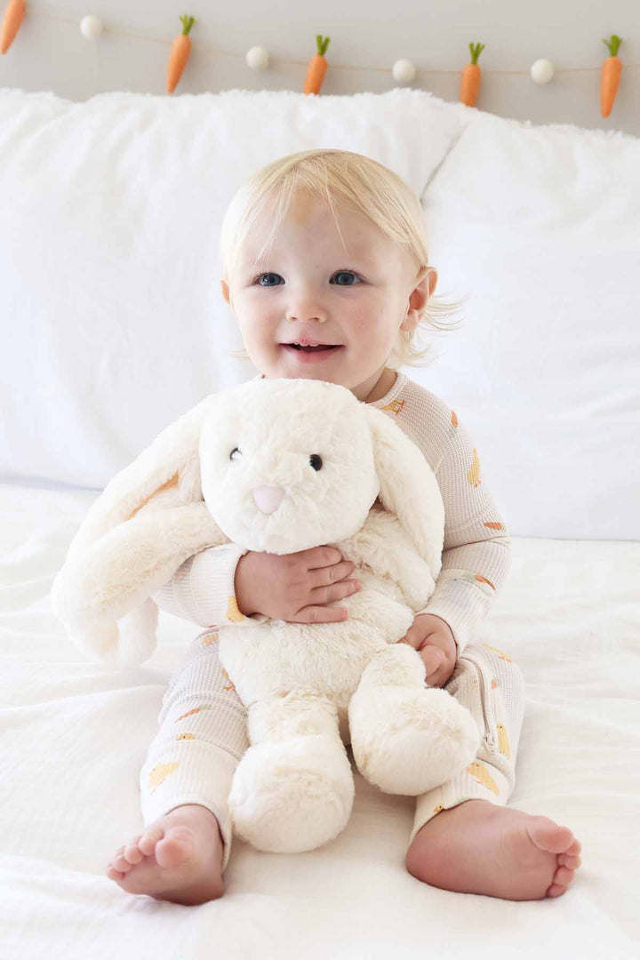 baby boy wearing an easter bamboo waffle pajama romper holding a white stuffed bunny animal