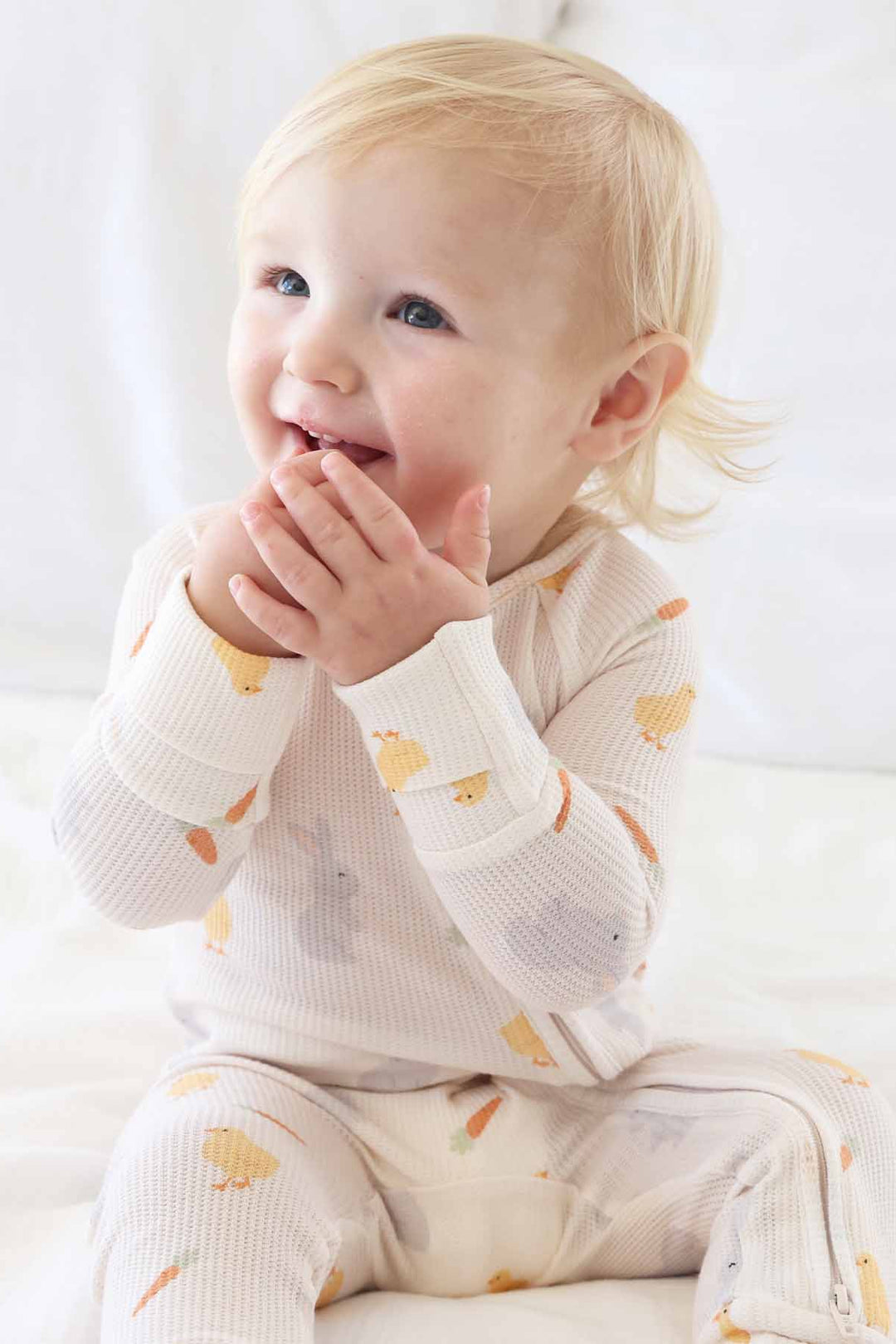 sitting baby boy with hands in his mouth wearing sweet peep bamboo waffle convertible zip romper pajama for babies and toddlers 