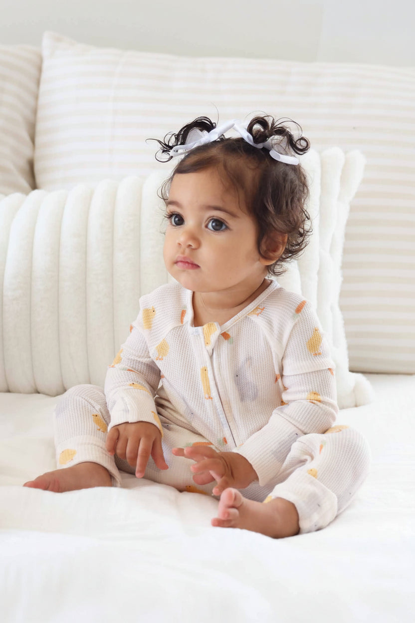 baby girl wearing easter bamboo waffle pajama romper with long sleeves and flip mitts and footies 