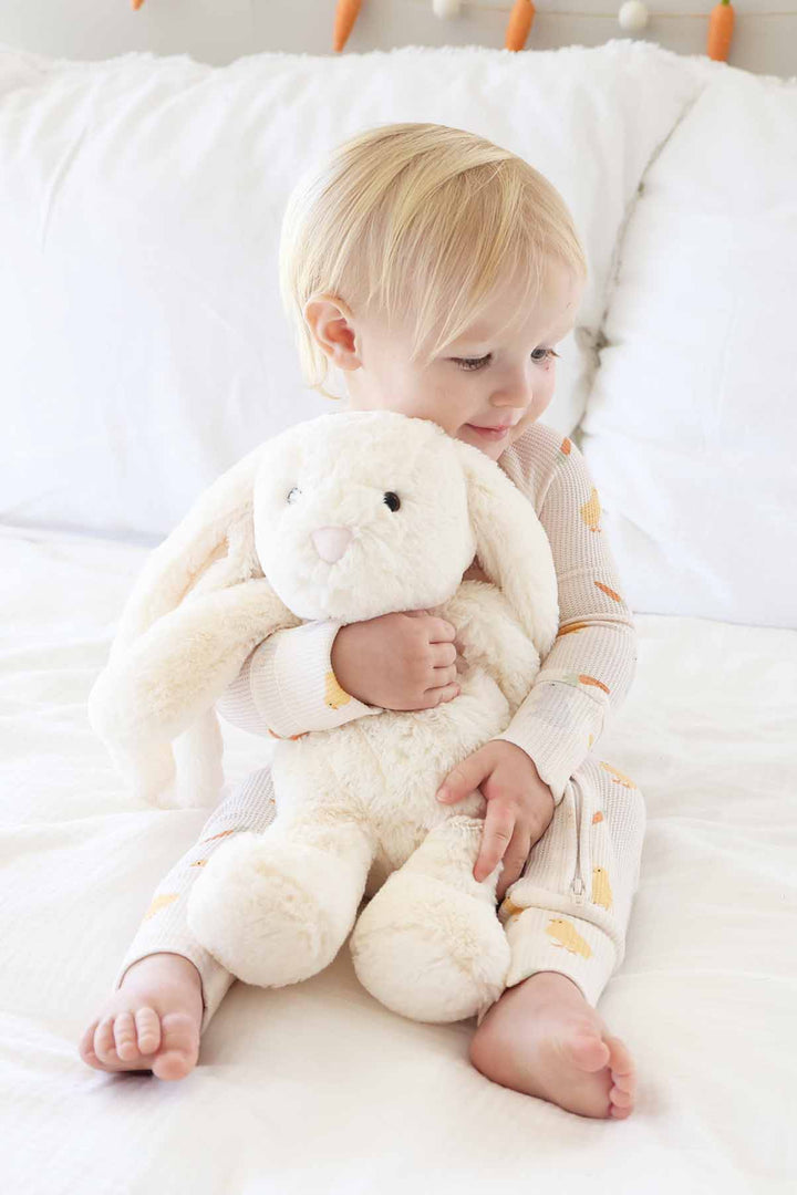 baby holding hugging a white stuffed bunny animal wearing the sweet peep easter convertible zip romper pajama 