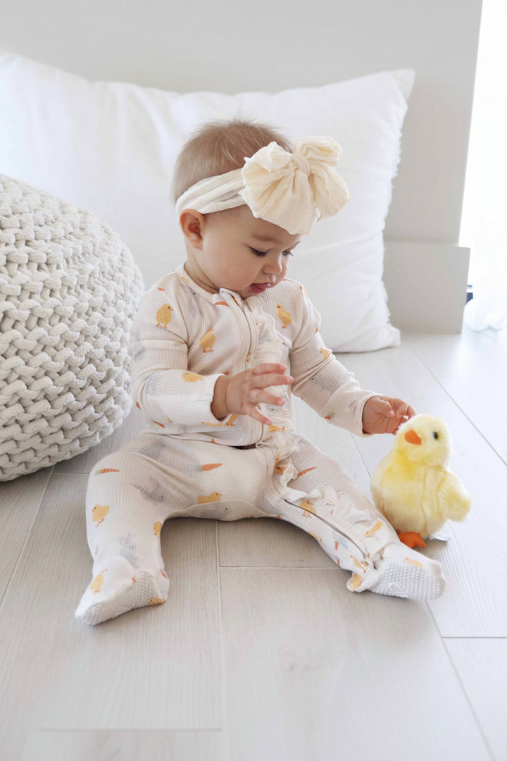 girl wearing easter bamboo waffle ruffle zipper footie with an off white ruffle bow headwrap