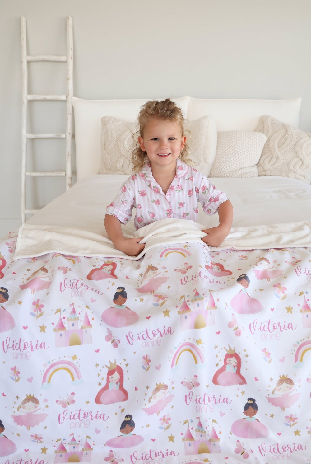little girl wrapped in a caden lane personalzied themed blanket, featuring princesses and castles. 