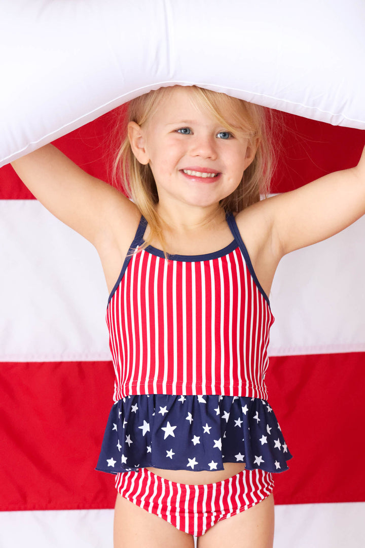 girl standing with innertube over her head in stars & stripes tankini 
