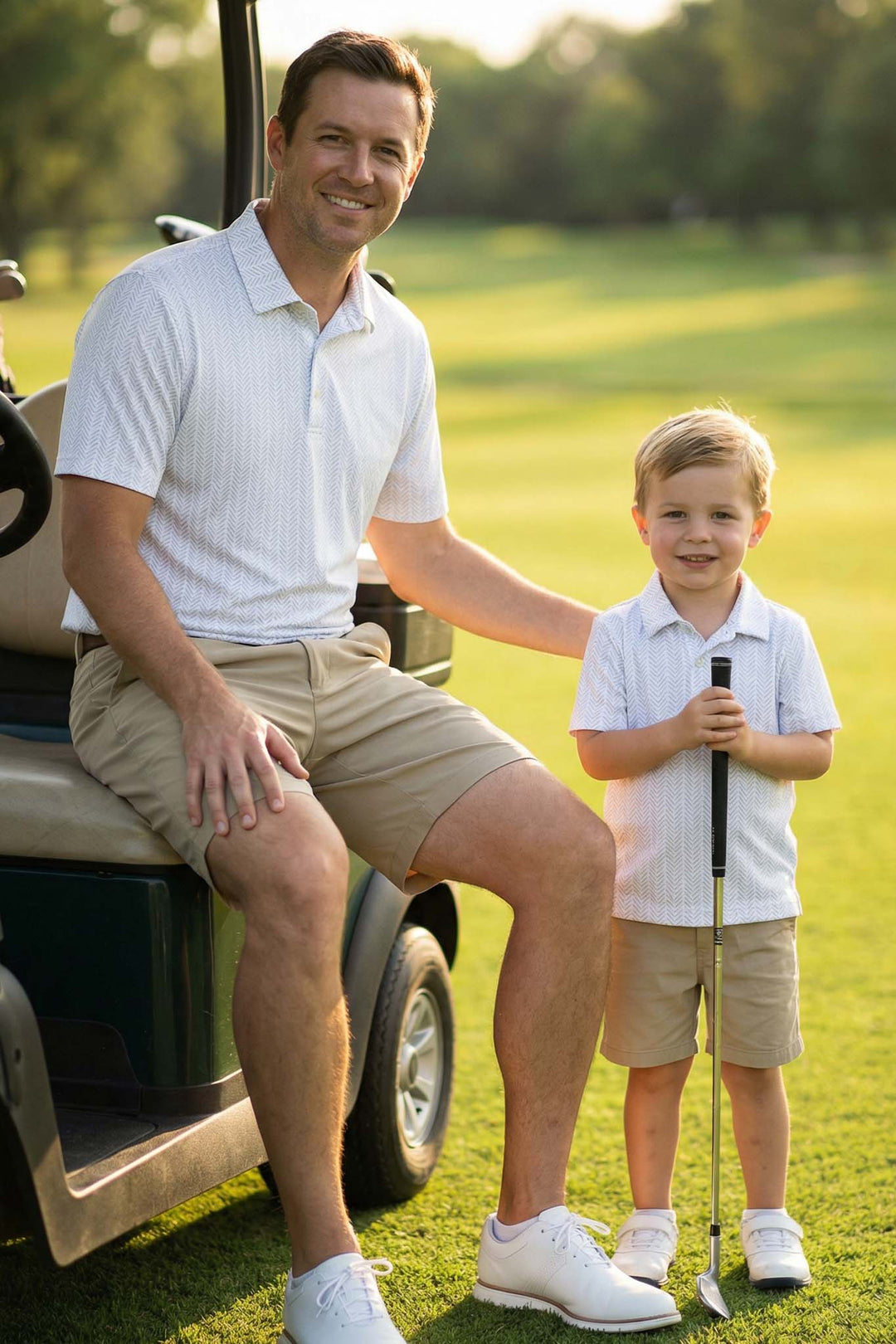 dad sitting on golf cart with arm around son holding a golf club and wearing matching collared shirts 