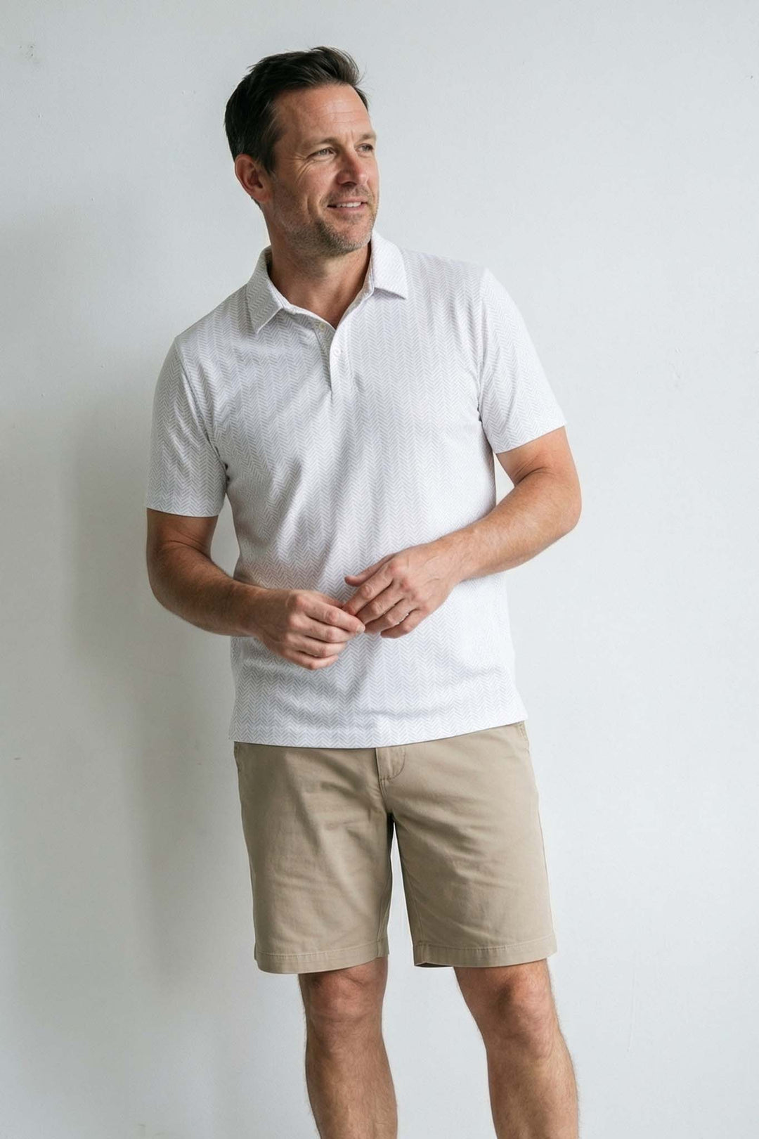 dad standing against wall wearing white polo shirt with golf balls and tees