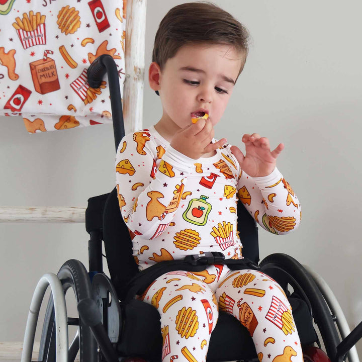 little boy in wheelchair wearing a food themed two piece pajama set for kids 