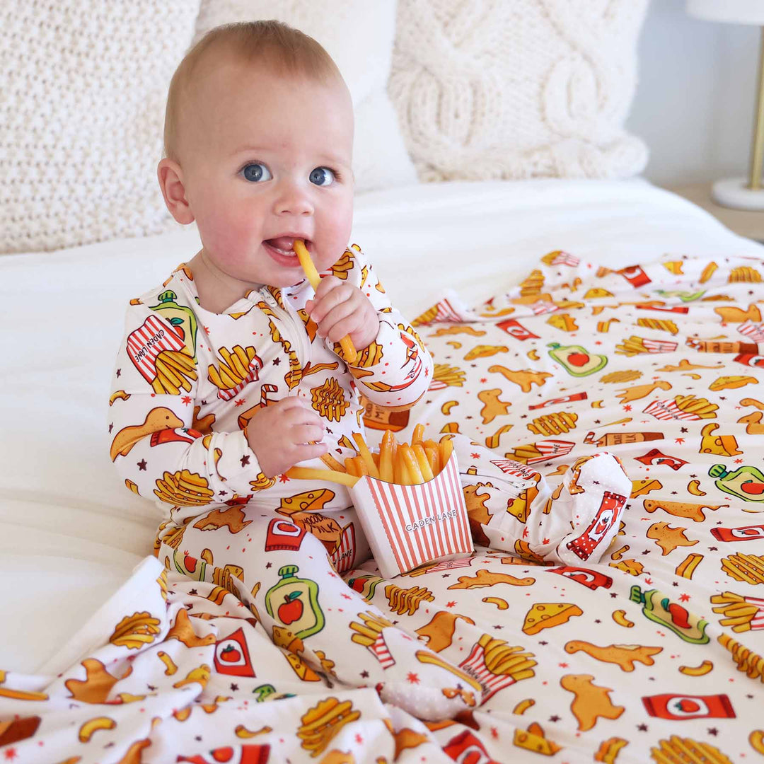 baby wearing a food themed zipper footie eating fake french fries