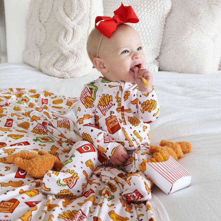 baby girl wearing a fast food themed footie eating a fake french fry with chicken nuggets around her