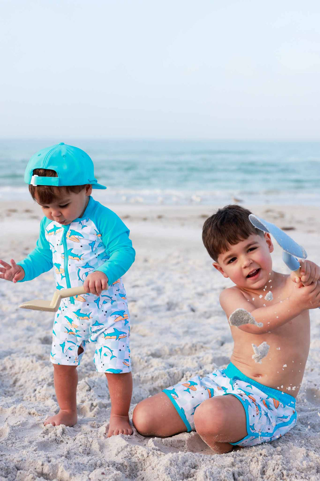 two boys playing in the sand in surfing sharks swimsuits 