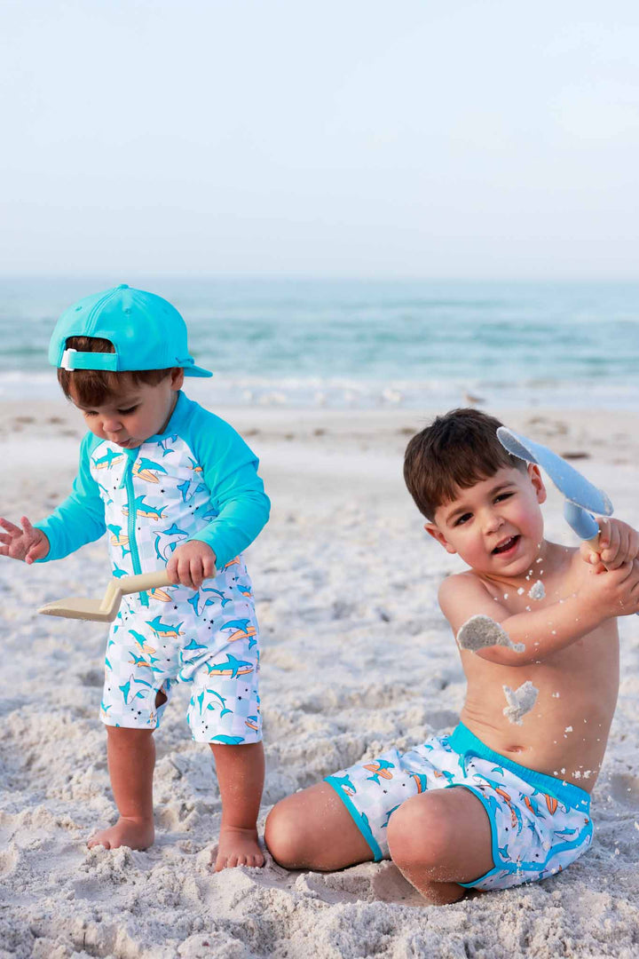two boys playing in the sand in surfing sharks swimsuits 