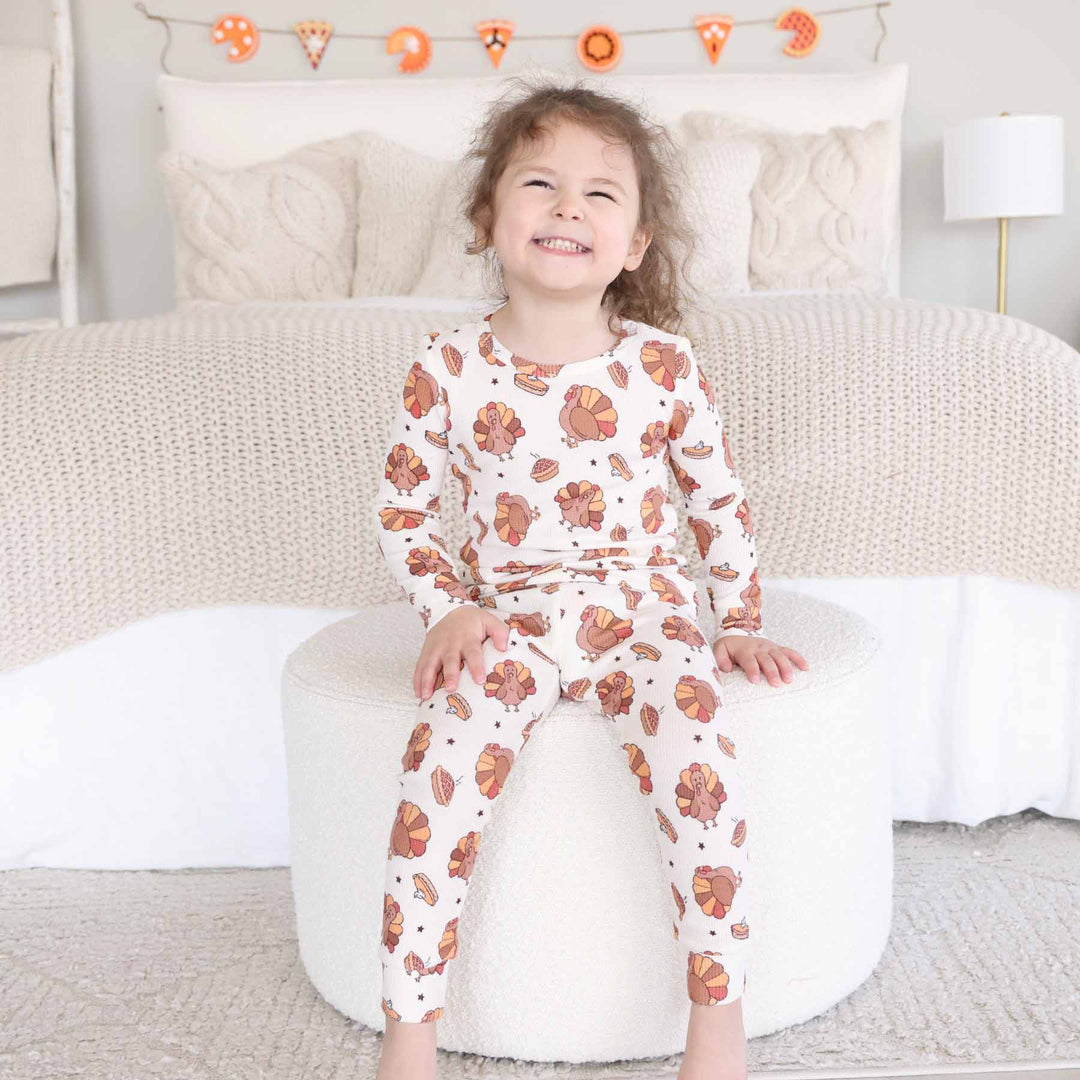 girl wearing thanksgiving pajama set sitting on ottoman