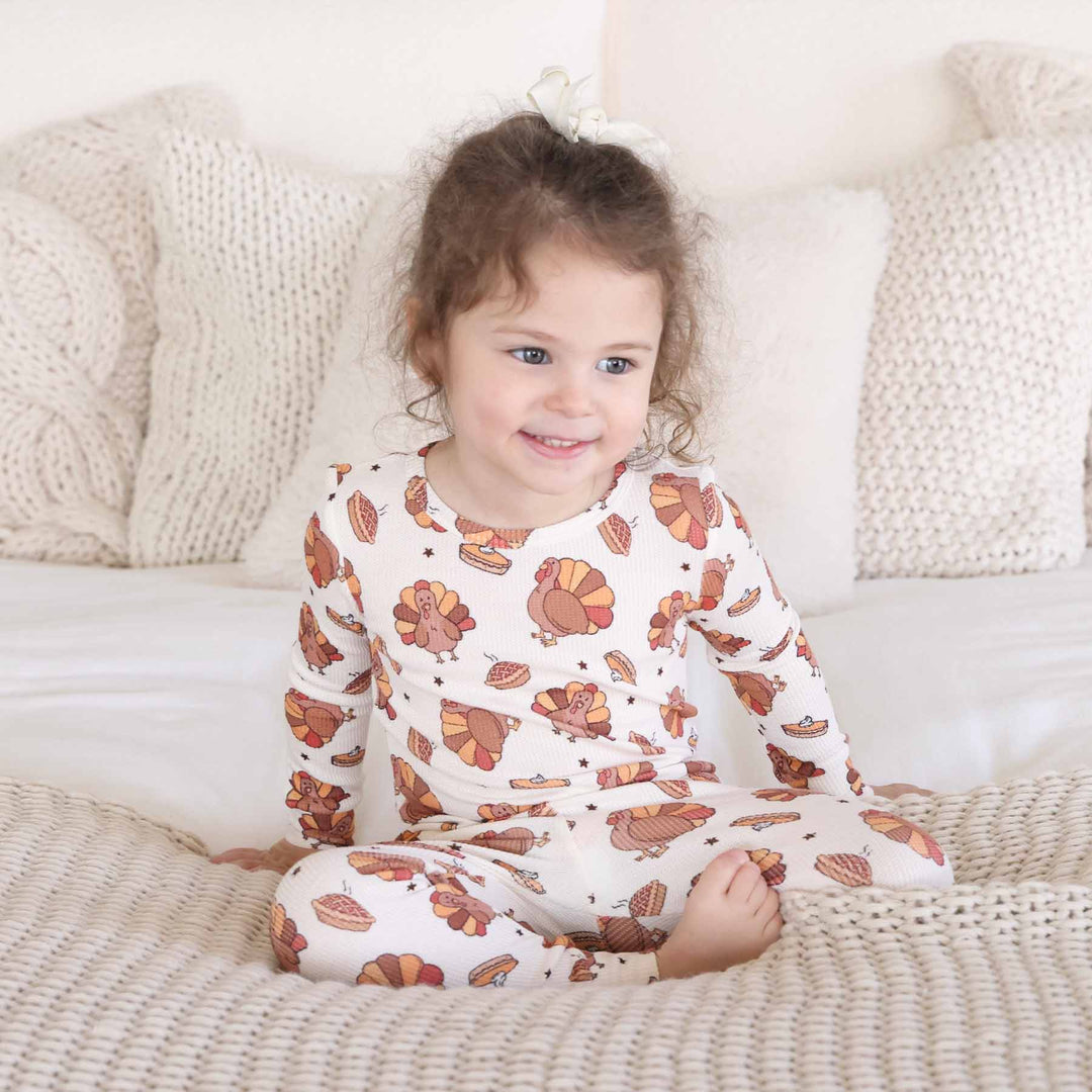 girl sitting on bed wearing thanksgiving two piece pajama set 